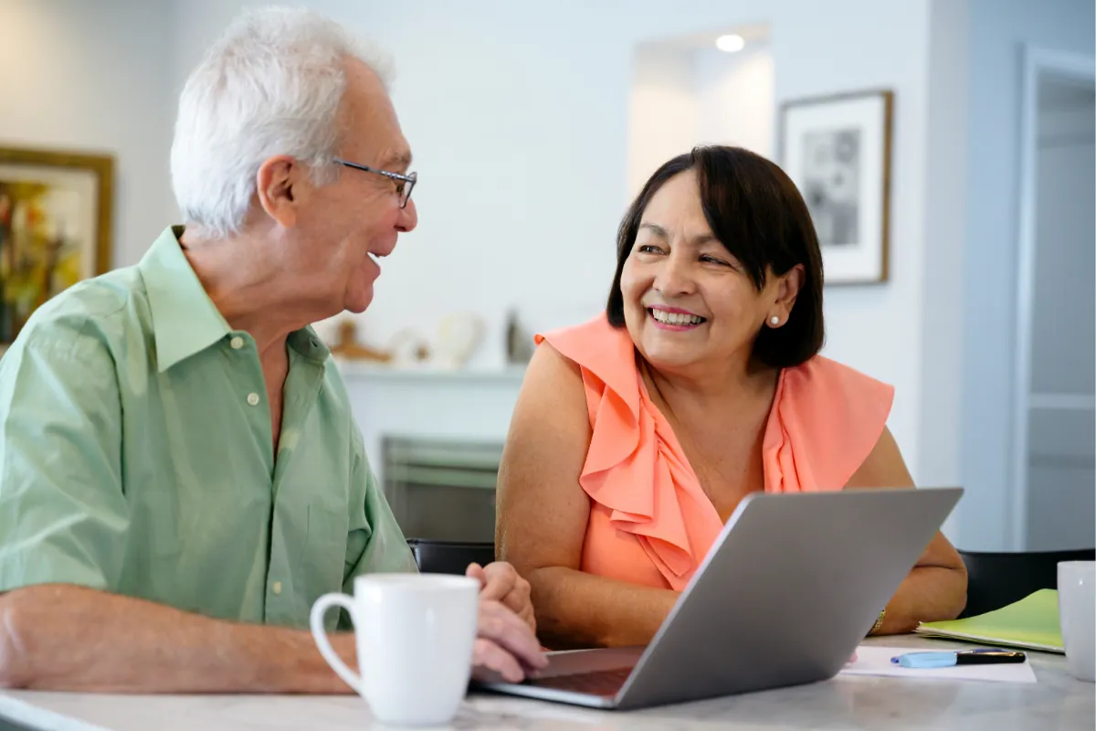 A smiling couple looking at a laptop together