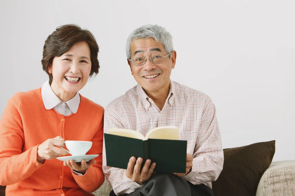 A smiling couple enjoying a book and a cup of tea together